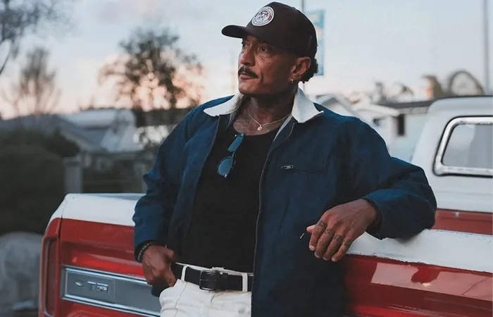 Jesse Ryan leaning against a pickup truck at sunset.