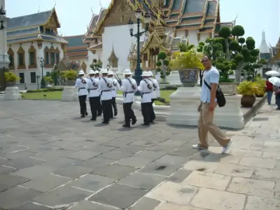 Rob Tatum walking through a temple courtyard, with uniformed guards and ornate traditional buildings in the background.