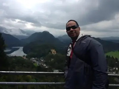 Rob Tatum standing at a scenic mountain overlook with a lake and cloudy sky in the background.