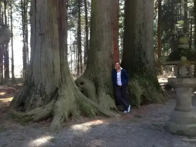 Rob Tatum standing beside massive old-growth trees in a forest setting.