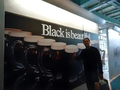 Rob Tatum standing beside a large “Black is beautiful” display in a modern indoor public space.