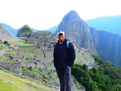 Rob Tatum standing at Machu Picchu with mountain peaks and ancient stone ruins in the background.