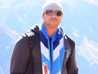 Rob Tatum wearing sunglasses and winter gear, posing outdoors with snowy mountains in the background.
