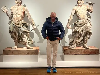 Rob Tatum standing between two large classical marble statues in a museum gallery.