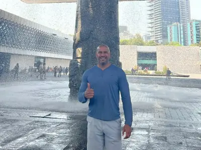 Rob Tatum giving a thumbs-up while standing in front of a large fountain in an outdoor plaza.