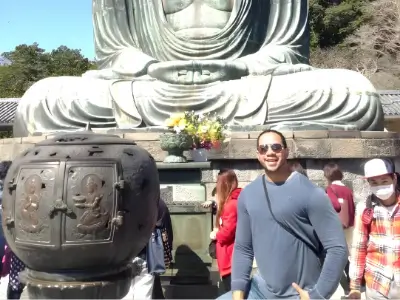Rob Tatum standing in front of a large Buddha statue at a temple with other visitors nearby.