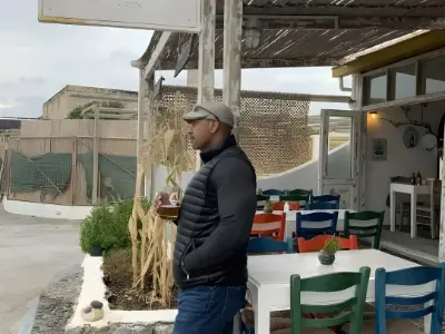 Rob Tatum standing outside a seaside café holding a drink.