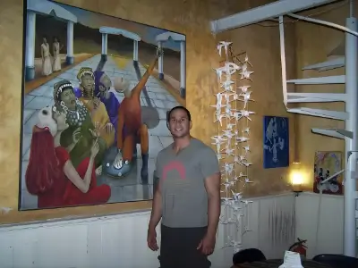 Rob Tatum standing indoors beside colorful artwork and hanging decorations.